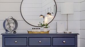 A vanity with a round mirror, two wall-mounted lamps, a fan, and a potted plant. - Downtown Ogunquit!  Steps to the Beach, Dining & Shops! Park & Walk Everywhere! (Ogunquit)
