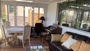 A sunlit living room with a piano, a glass coffee table, and a leather sofa. - Convenient Location Near Large Shopping Mall and Train Station. (Calgary)