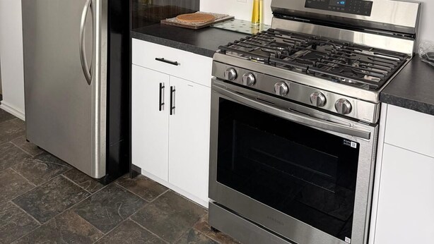 A kitchen with a stainless steel refrigerator, a gas stove, and a built-in oven. - Convenient Location Near Large Shopping Mall and Train Station. (Calgary)