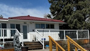 A house with a red roof, white exterior, and a wooden deck with a staircase leading to a porch. - Convenient Location Near Large Shopping Mall and Train Station. (Calgary)