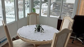 A conference room with a round table, four chairs, and a view of a snowy outdoor area through large windows. - Convenient Location Near Large Shopping Mall and Train Station. (Calgary)