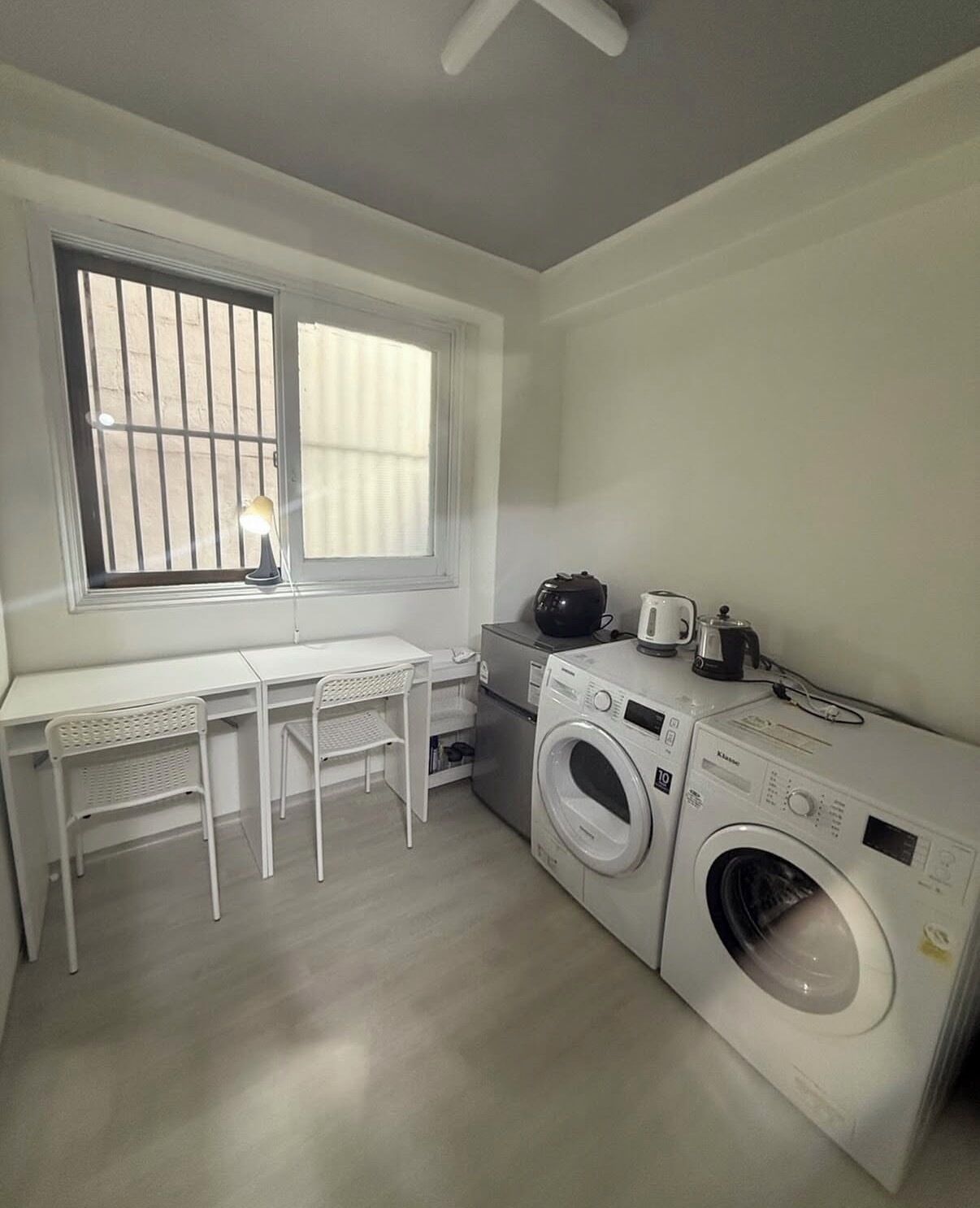 A compact laundry room with a washing machine, dryer, and a small table with chairs.