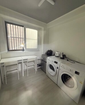 A compact laundry room with a washing machine, dryer, and a small table with chairs. - Affordable, Spacious 3-bedroom apartment in lovely Seoul with AC (Seoul)