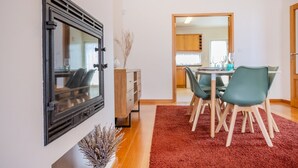 Un comedor con una mesa, sillas, un tapete rojo y un jarrón decorativo.