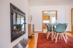 A dining area with a table, chairs, a red rug, and a decorative vase. - GuestReady - Casa Santa Maria (Ponta Delgada)