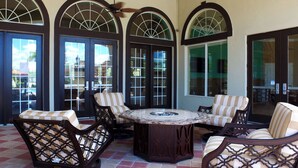 A patio area with a round table surrounded by four cushioned chairs, large arched windows, and a tiled floor. - Cozy 3BR Townhome - Pool - Bella Vida Resort! (Kissimmee)
