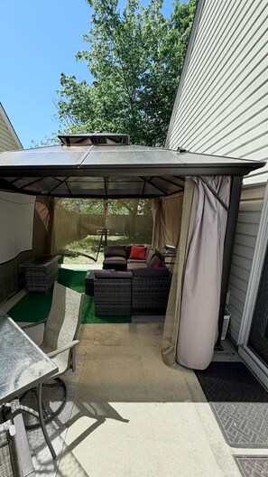Une terrasse extérieure dotée d’un espace salon couvert, d’une table et d’un petit espace de jeux.