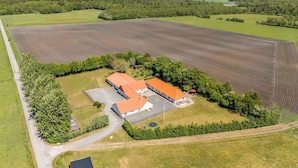 Vista aérea de una granja con dos edificios de techo rojo, un camino pavimentado y campos aledaños.
