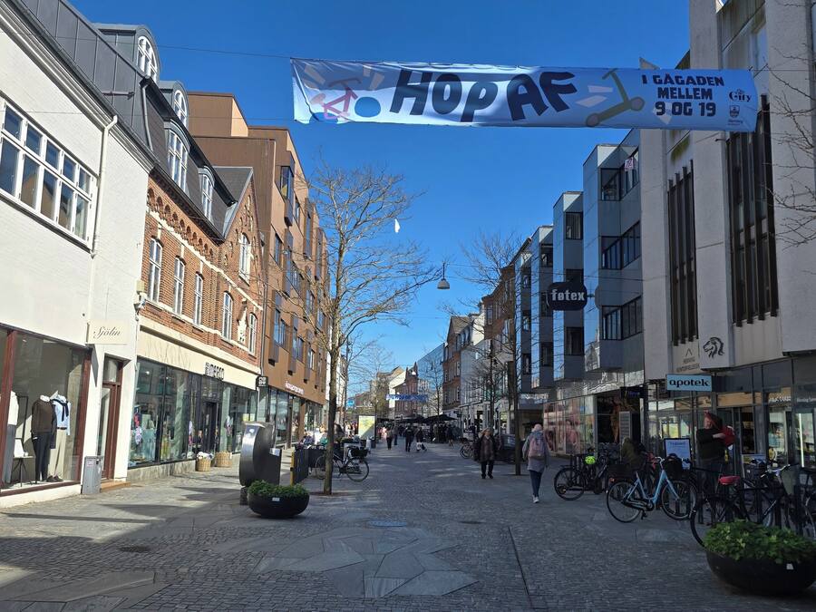 A cobblestone street lined with shops and buildings, a banner with 'HOPAF' text, and a sign indicating a 3.5t vehicle weight limit.