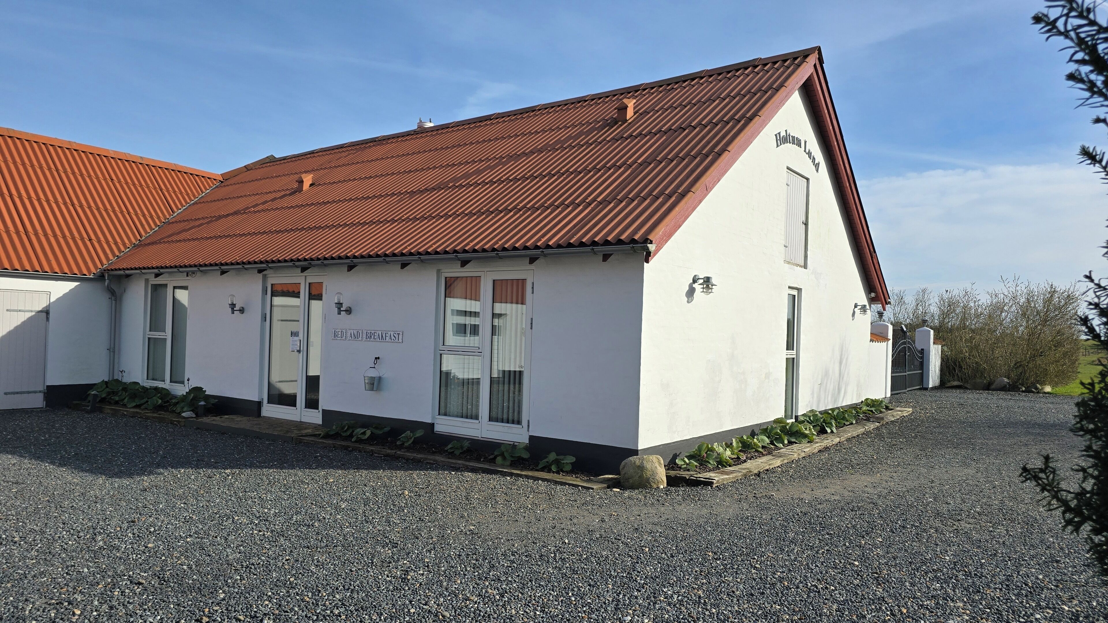 A building with a white exterior, a red roof, and a sign indicating it offers bed and breakfast services.