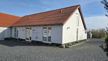 A building with a white exterior, a red roof, and a sign indicating it offers bed and breakfast services.