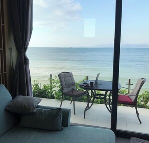 Ein Zimmer mit Meerblick, eine Couch, ein Tisch mit einem Laptop und zwei Stühle.