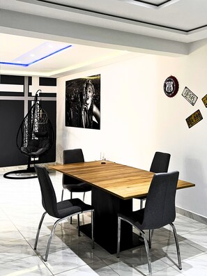 Una sala de conferencias moderna con una mesa de madera, sillas negras, una silla colgante y decoraciones en la pared, incluyendo un cartel de Route 66 y placas de matrícula.