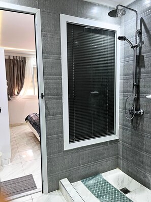 Un baño moderno con ducha, inodoro y ventana con persianas.