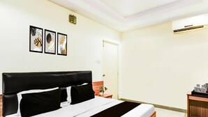 A hotel room with a bed, bedside table, and a small desk with a chair. - Deluxe Red Hills Lakdikapul Sitara Grand (Hyderabad)