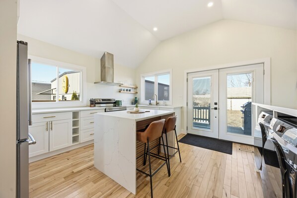 A modern kitchen with a large island, bar stools, and a built-in oven.