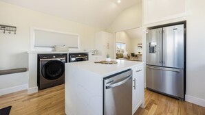 Una cocina moderna con lavadora integrada, refrigerador de acero inoxidable y una isla con encimera de mármol.