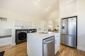 A modern kitchen with a built-in washer, a stainless steel refrigerator, and a marble countertop island.