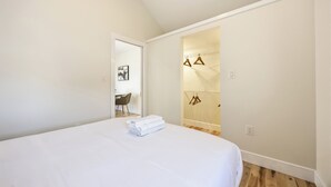 Un dormitorio con una cama grande, una puerta que da a un baño y una pequeña mesa con sillas.