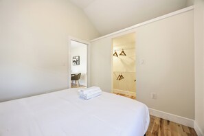 A bedroom with a large bed, a door leading to a bathroom, and a small table with chairs.