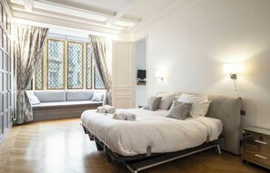 Ein Schlafzimmer mit Bett, Fensterbank, Nachttisch und Lampe.