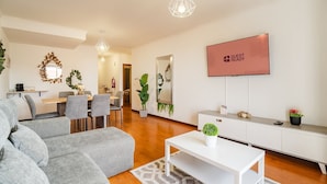 Un salon moderne comprenant un canapé, une table à manger, des chaises, un téléviseur et une cheminée.