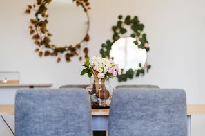 A dining table with a vase of flowers, two gray chairs, and a mirror on the wall. - GuestReady - Luna's Apartment (Caniço)