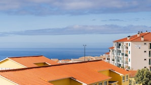 Un quartier résidentiel situé sur la côte, caractérisé par des toits recouverts de tuiles en terre cuite, des balcons et une vue dégagée sur la mer.