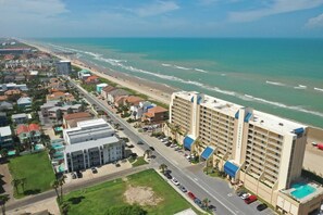 Een kusthotel met uitzicht op het strand, meerdere verdiepingen en een parkeerplaats.