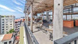 Een terras op het dak met hangstoelen, een bar en uitzicht op de skyline.