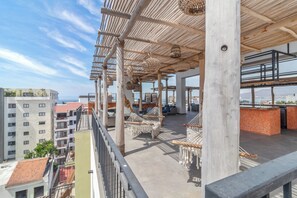 A rooftop terrace with hanging chairs, a bar area, and a view of the cityscape. - Exclusive condo steps away from the sea | Top location Zona Dorada Bucerias (Bucerías)