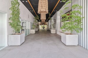 A corridor with potted plants, a hanging light fixture, and a glass door on the left. - Exclusive condo steps away from the sea | Top location Zona Dorada Bucerias (Bucerías)