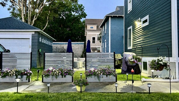 A residential area with houses, a lawn, and flower planters. - Modern 3BR Apt 1st Fl Parking, WiFi, Laundry, Walk to 30+ Shops & Restaurants (Providence)