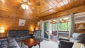 A wooden-paneled room with a sofa, armchairs, and a table. - Juniper Presents: Chalet #56 Screened Porch, Pool & Resort Amenities (Stevensville)