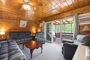 A wooden-paneled room with a sofa, armchairs, and a table.