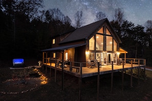 A cabin with a deck, a fireplace, and a starry night sky. - BaseCamp Bryson-Panoramic Views-Pet Friendly-Paved-Hot Tub-Fire-pit (Bryson City)