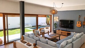 Ein modernes Wohnzimmer mit einer großen Couch, einem Couchtisch, einem Fernseher und einem Balkon mit Sitzgelegenheit.