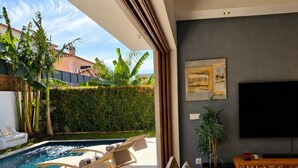 Ein modernes Wohnzimmer mit Pool, Holzmöbeln und einem großen Fernseher.