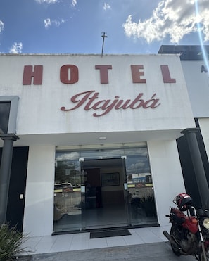 Un hotel llamado 'HOTEL Itajuba' con una entrada visible y una motocicleta estacionada afuera.