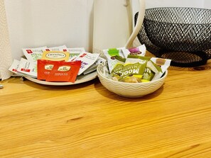 A table with a plate of food packets and a bowl of snacks.