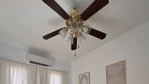 A room with two beds, a ceiling fan, an air conditioning unit, and two framed artworks on the wall. - Spacious 3BR Apartment w Rooftop Terrace&Jacuzzi (Mersa Matruh)