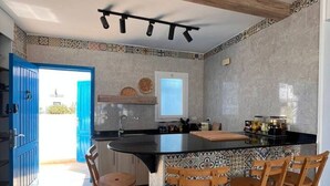 A modern kitchen with a central island, bar stools, and a view of the outside. - Spacious 3BR Apartment w Rooftop Terrace&Jacuzzi (Mersa Matruh)
