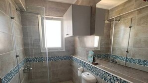 A bathroom with a shower, toilet, sink, and a window. - Spacious 3BR Apartment w Rooftop Terrace&Jacuzzi (Mersa Matruh)