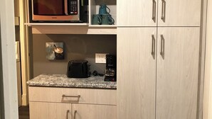 A kitchen with light wood cabinetry, a microwave, a toaster, and a coffee maker.
