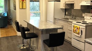 A modern kitchen with a central island, bar stools, a built-in oven, and a view to the outdoors.