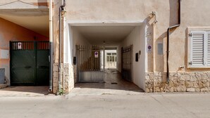 A building entrance with a gated driveway, a no parking sign, and a stone wall. - Apartment 200 Meters From the Beach (Castelsardo)