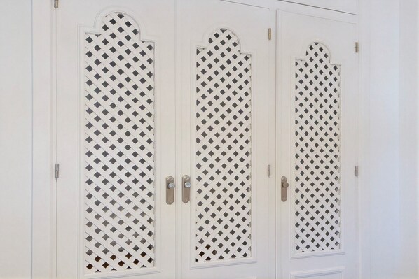 Three white doors with diamond lattice patterns and silver handles.