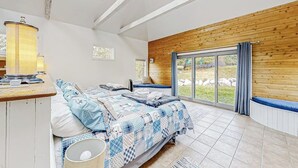 Ein Schlafzimmer mit zwei Betten, einer Holzwand, einem großen Fenster und einem Oberlicht.