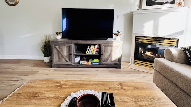 Ein Wohnzimmer mit Flachbildfernseher auf einem Holzschrank, Kamin und Sofa.