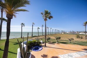 Un patio con palmeras, una piscina y vista al océano.